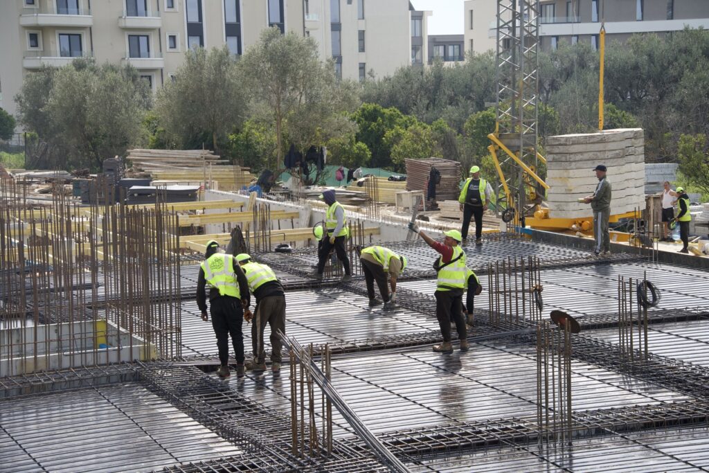 Construction team in high-visibility vests on the Radhimë foundation slab